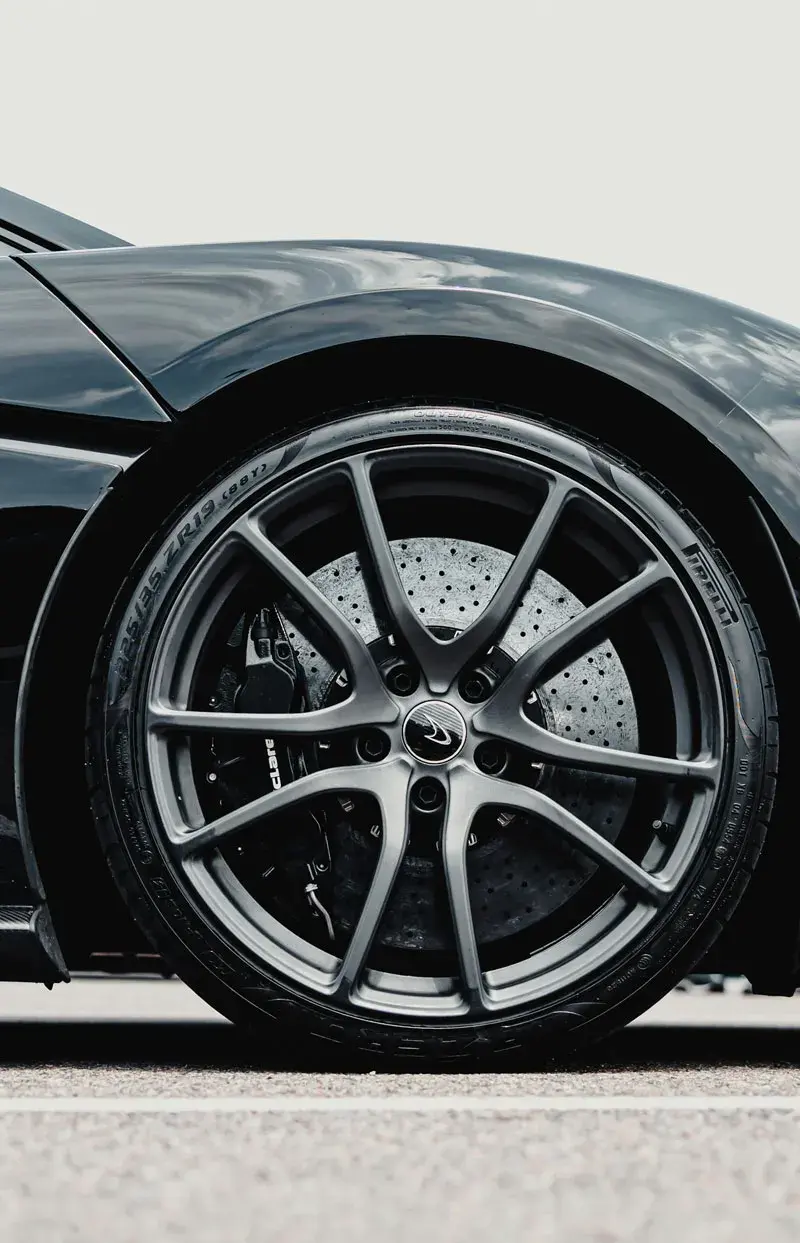Restored gleaming luxury alloy wheel on a dark performance car under dramatic studio lighting at AZ Rim Repair