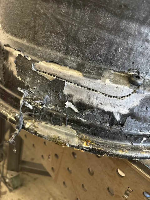 Backside of the same wheel mid-repair with a raw TIG weld bead along the crack