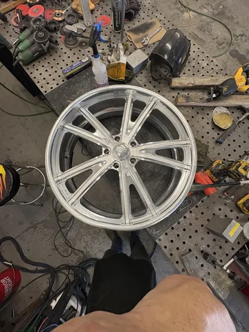 Billet 26-inch Intro wheel with a visibly bent barrel, on the shop workbench before repair